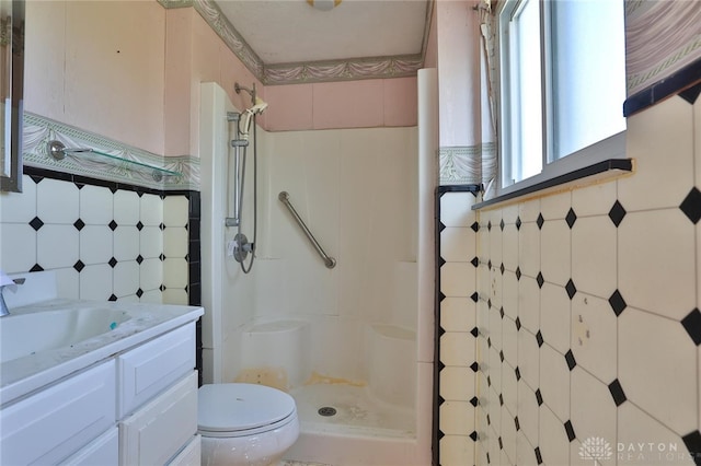 full bath featuring tile walls, vanity, toilet, and a stall shower