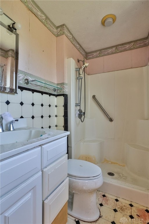 bathroom with a shower stall, toilet, vanity, and tile patterned floors
