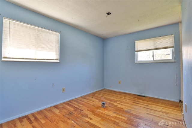 empty room with baseboards, wood finished floors, and visible vents