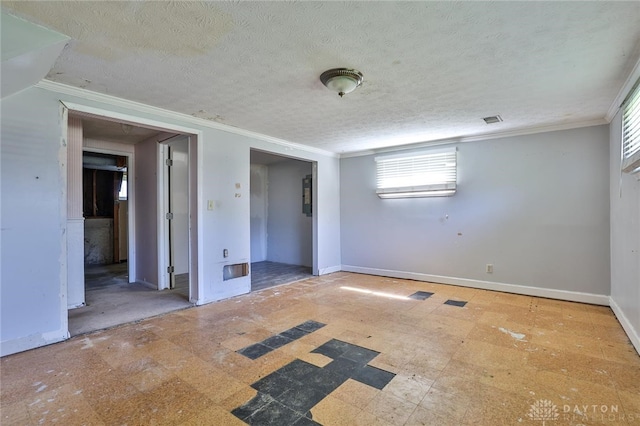 unfurnished room with baseboards, crown molding, a textured ceiling, and visible vents