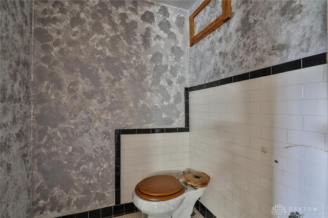 bathroom with toilet, wallpapered walls, and tile walls