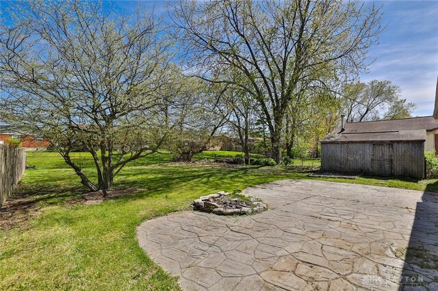 view of yard featuring an outdoor structure, fence, and a patio area