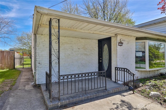 view of exterior entry featuring fence and covered porch