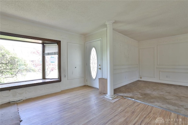 foyer entrance featuring crown molding, a textured ceiling, visible vents, and ornate columns