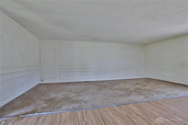 spare room with a decorative wall, a textured ceiling, and carpet