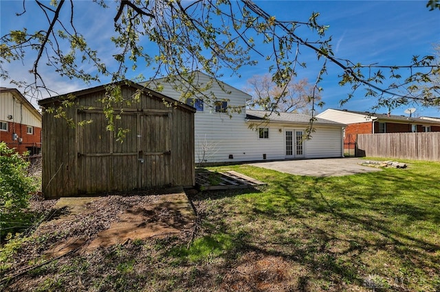 rear view of property featuring a patio area, a storage shed, french doors, fence, and a yard