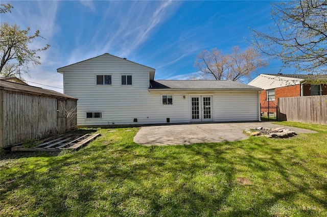 back of property featuring french doors, an outbuilding, fence, a yard, and a patio