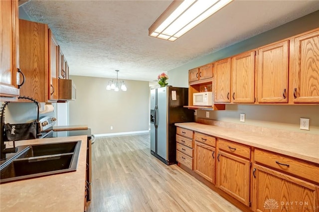 kitchen with white microwave, an inviting chandelier, fridge with ice dispenser, a textured ceiling, and range with electric cooktop