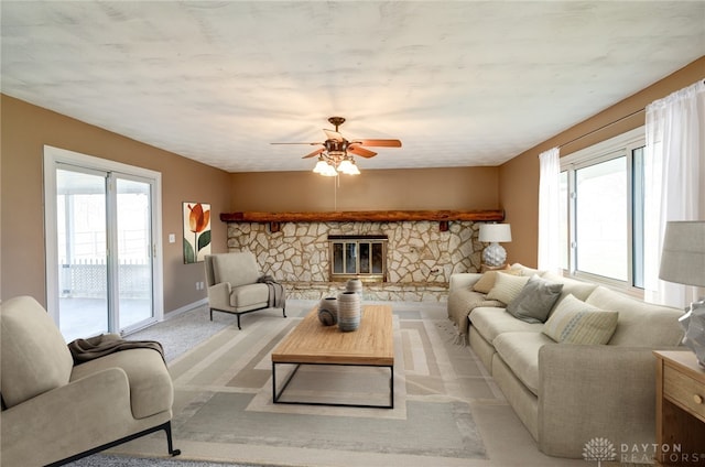 carpeted living area with a fireplace, baseboards, and a ceiling fan