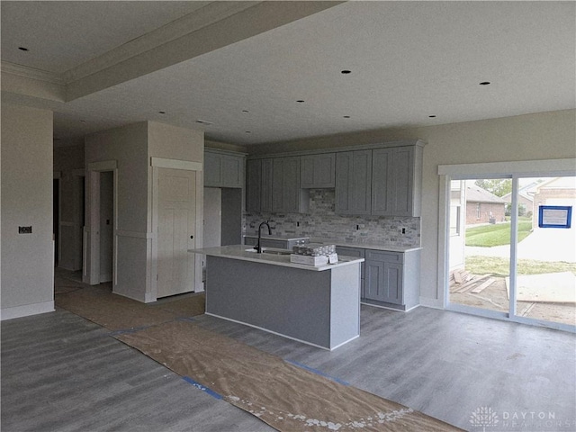 2223 Tandem Dr, Xenia, OH 45385 - kitchen with wood finished floors, gray cabinets, tasteful backsplash, an island with sink, and ornamental molding