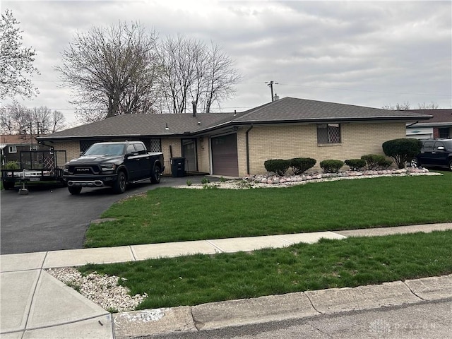 view of front of house featuring aphalt driveway, brick siding, a front lawn, and an attached garage