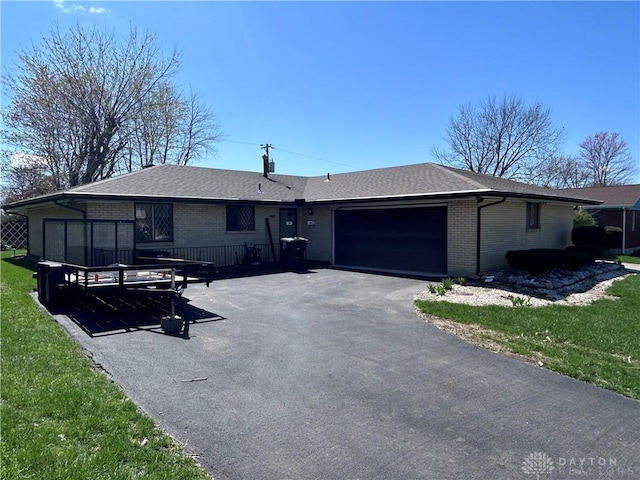 ranch-style home with brick siding, roof with shingles, a garage, and aphalt driveway