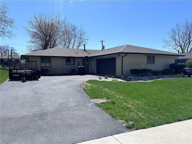 single story home featuring aphalt driveway, a front yard, brick siding, and an attached garage