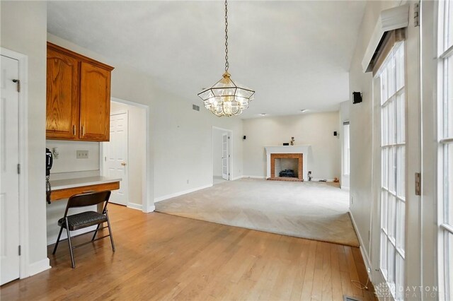 433 Vincent Ct, Middletown, OH 45042 - unfurnished living room with a chandelier, light wood-style floors, baseboards, a fireplace, and an office area