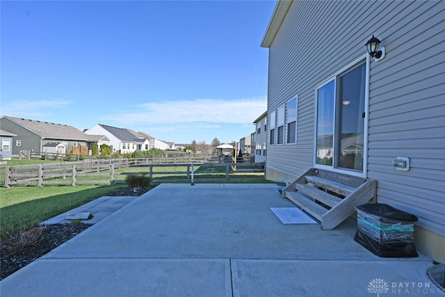 view of patio with entry steps, fence, and a residential view
