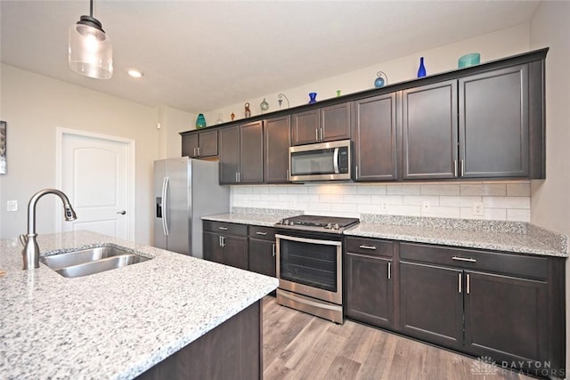 kitchen with tasteful backsplash, a sink, dark brown cabinetry, light wood finished floors, and stainless steel appliances