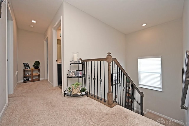 hall featuring recessed lighting, an upstairs landing, light colored carpet, and baseboards