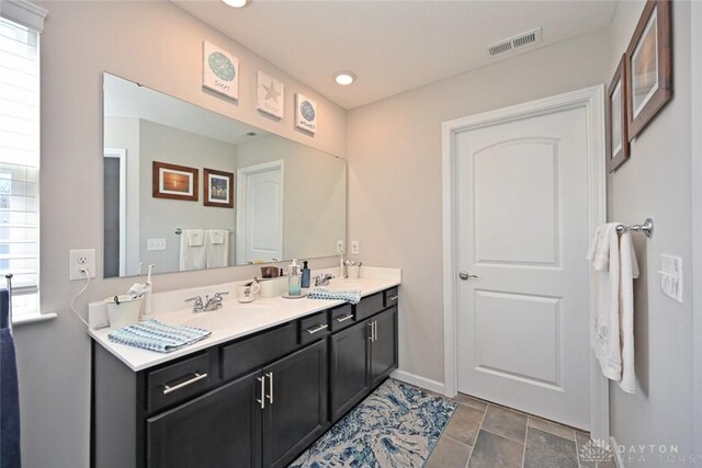 bathroom with double vanity, visible vents, baseboards, and a sink