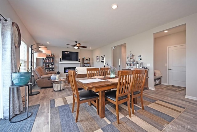 dining area with wood finished floors, ceiling fan, a glass covered fireplace, and recessed lighting