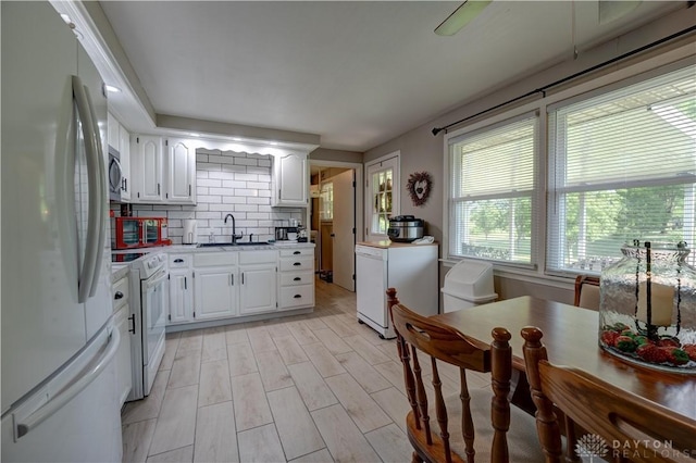 kitchen with light countertops, a sink, white appliances, and white cabinets