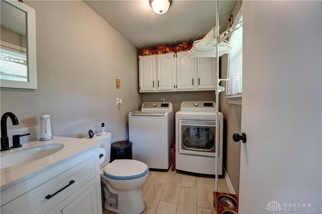 laundry area featuring a sink, independent washer and dryer, laundry area, and light wood-style flooring