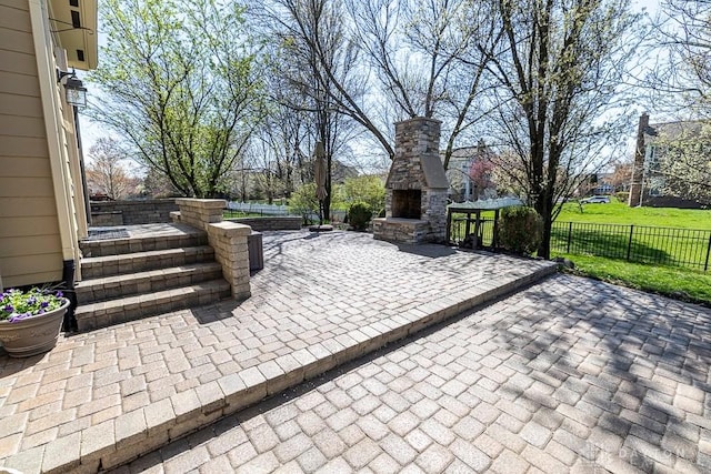 view of patio / terrace featuring fence and an outdoor stone fireplace