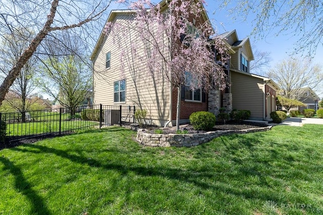 view of side of home featuring fence and a lawn