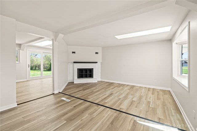 4433 Lambeth Dr, Dayton, OH 45424 - unfurnished living room with a skylight, baseboards, a brick fireplace, and light wood finished floors