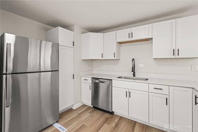 4433 Lambeth Dr, Dayton, OH 45424 - kitchen featuring appliances with stainless steel finishes, a sink, light wood finished floors, light countertops, and white cabinetry