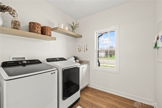 2164 Northbridge Trl, Troy, OH 45373 - clothes washing area with washing machine and dryer, cabinet space, light wood finished floors, and baseboards