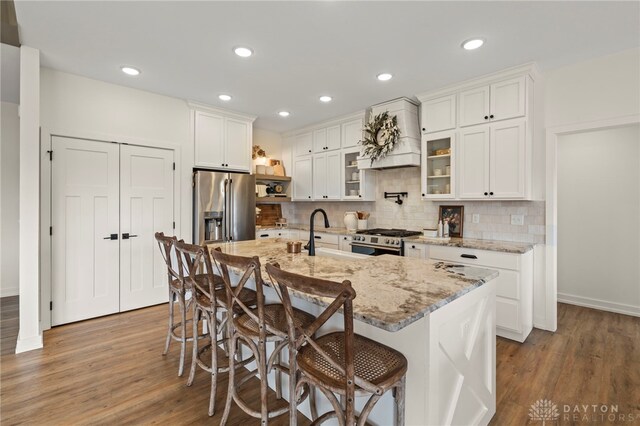 2164 Northbridge Trl, Troy, OH 45373 - kitchen with stainless steel appliances, wood finished floors, a sink, premium range hood, and white cabinets