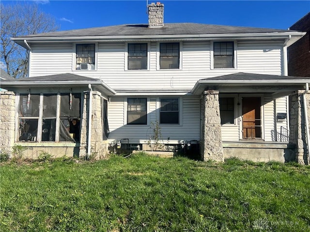 rear view of property with a sunroom, covered porch, a lawn, a chimney, and cooling unit