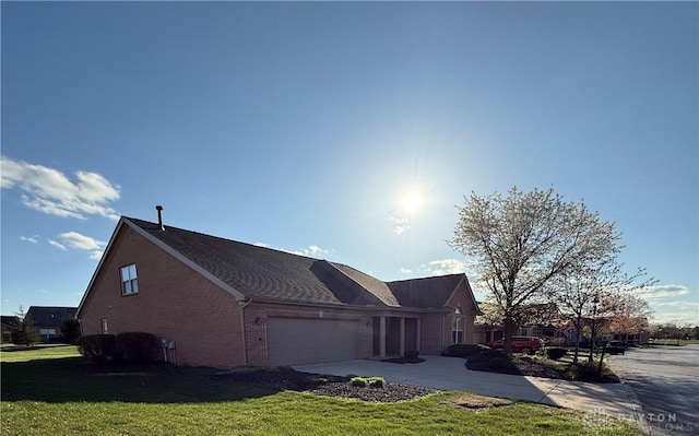 view of side of home with a yard, a garage, concrete driveway, and brick siding