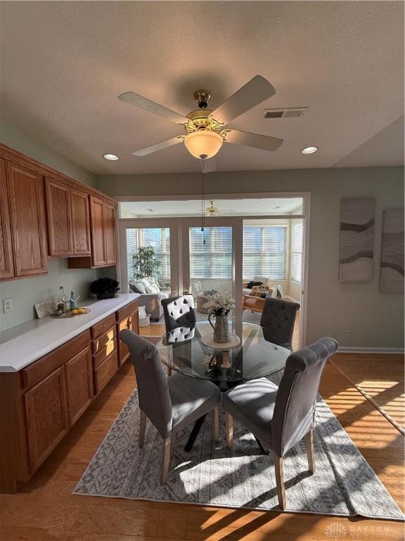 dining space with visible vents, ceiling fan, light wood finished floors, and a healthy amount of sunlight