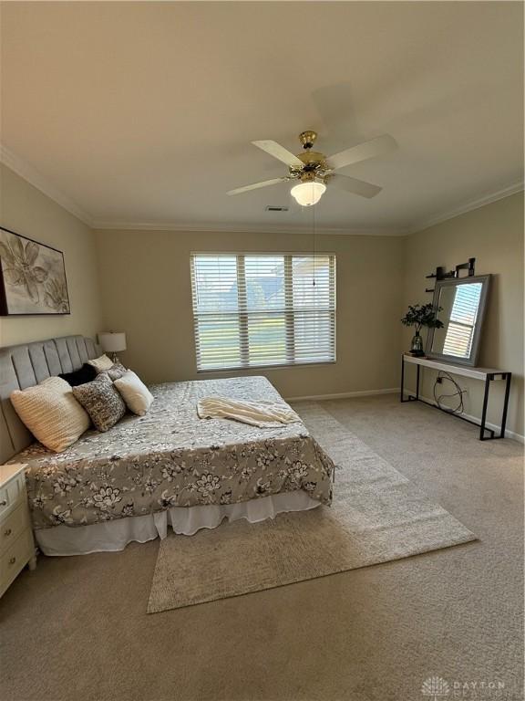 carpeted bedroom with baseboards, crown molding, and a ceiling fan