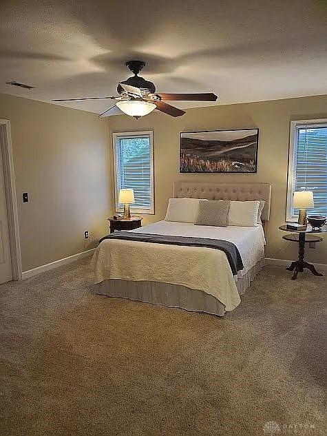 carpeted bedroom with visible vents, baseboards, and a ceiling fan