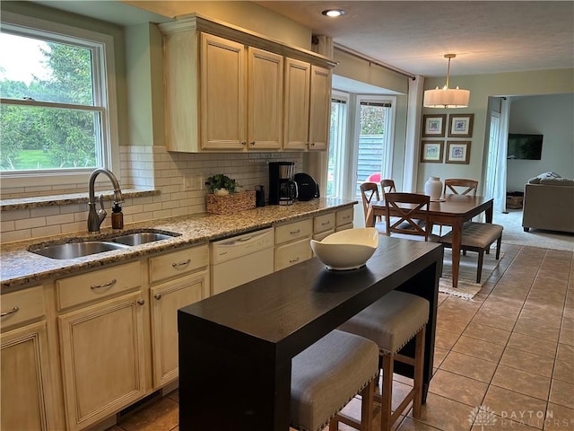 kitchen featuring a healthy amount of sunlight, tasteful backsplash, white dishwasher, and a sink