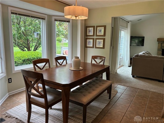 carpeted dining room with a wealth of natural light, baseboards, and tile patterned floors