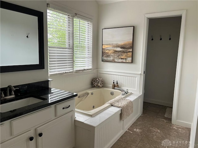 full bath with vanity, a whirlpool tub, a wealth of natural light, and baseboards