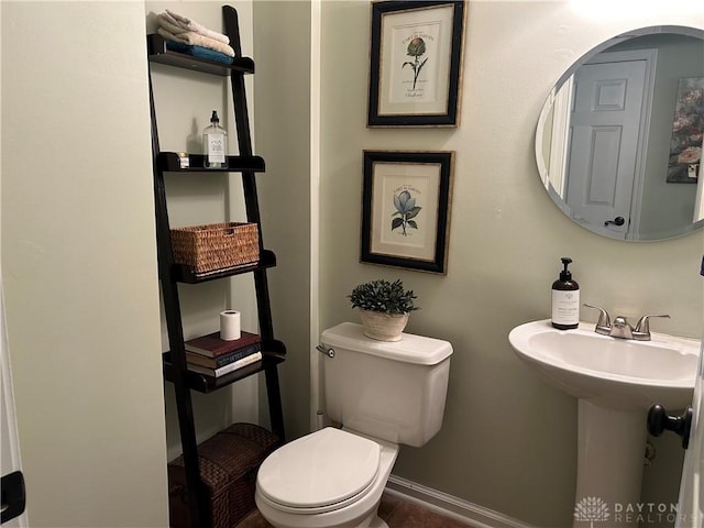 half bath with toilet, baseboards, and tile patterned floors