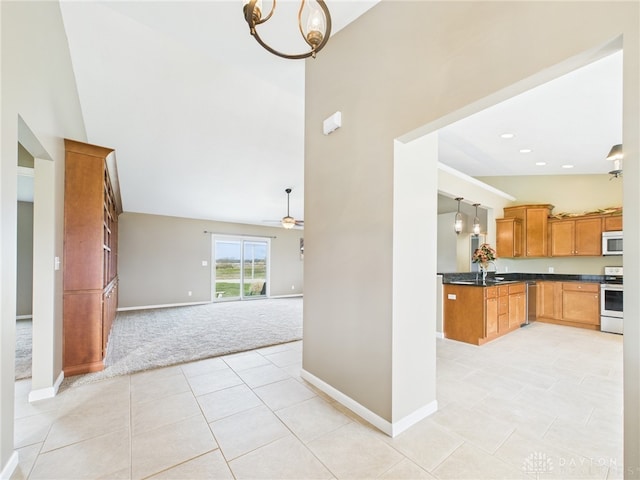 kitchen with open floor plan, dark countertops, appliances with stainless steel finishes, high vaulted ceiling, and light colored carpet