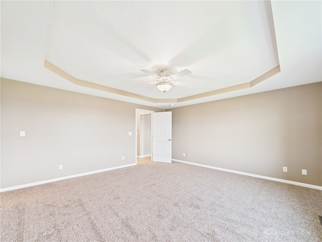 spare room featuring carpet flooring, baseboards, a ceiling fan, and a raised ceiling