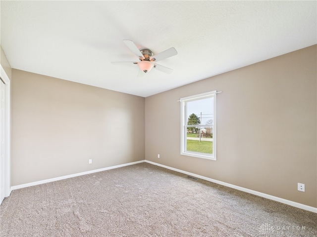 carpeted empty room featuring visible vents, baseboards, and a ceiling fan