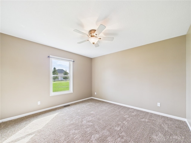 empty room with baseboards, a ceiling fan, visible vents, and carpet floors