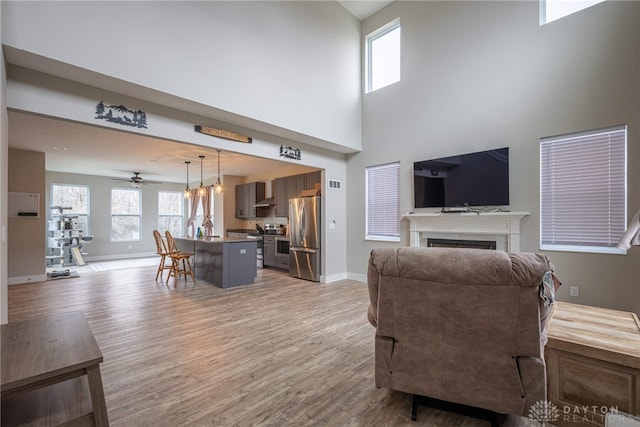 living room with light wood-type flooring, a fireplace, baseboards, and visible vents
