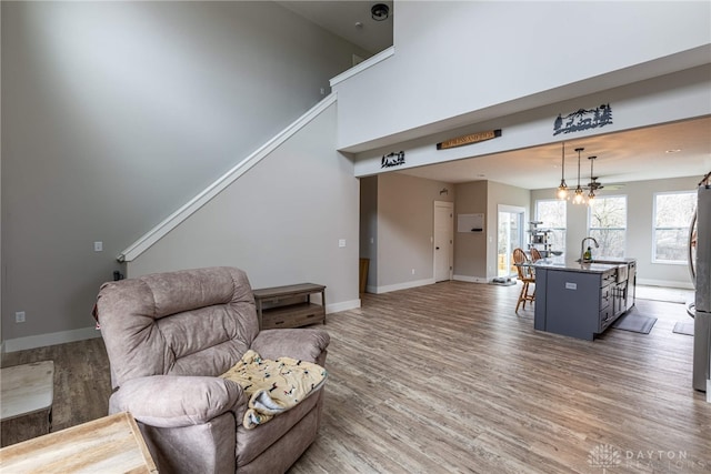 living area with a towering ceiling, light wood-type flooring, and baseboards