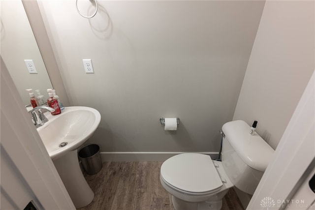 bathroom with baseboards, a sink, toilet, and wood finished floors