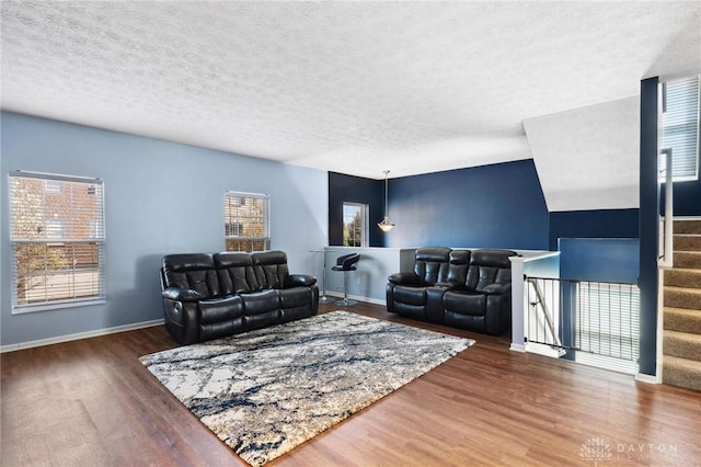 living area with baseboards, plenty of natural light, wood finished floors, and a textured ceiling