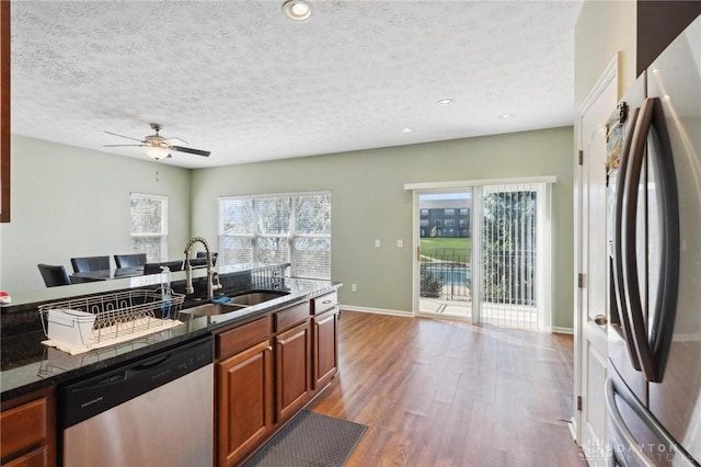 kitchen with wood finished floors, a healthy amount of sunlight, a sink, and appliances with stainless steel finishes