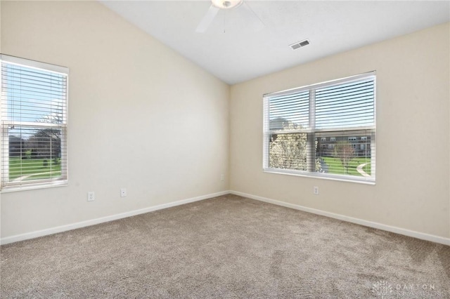 carpeted spare room featuring visible vents, baseboards, vaulted ceiling, and a ceiling fan